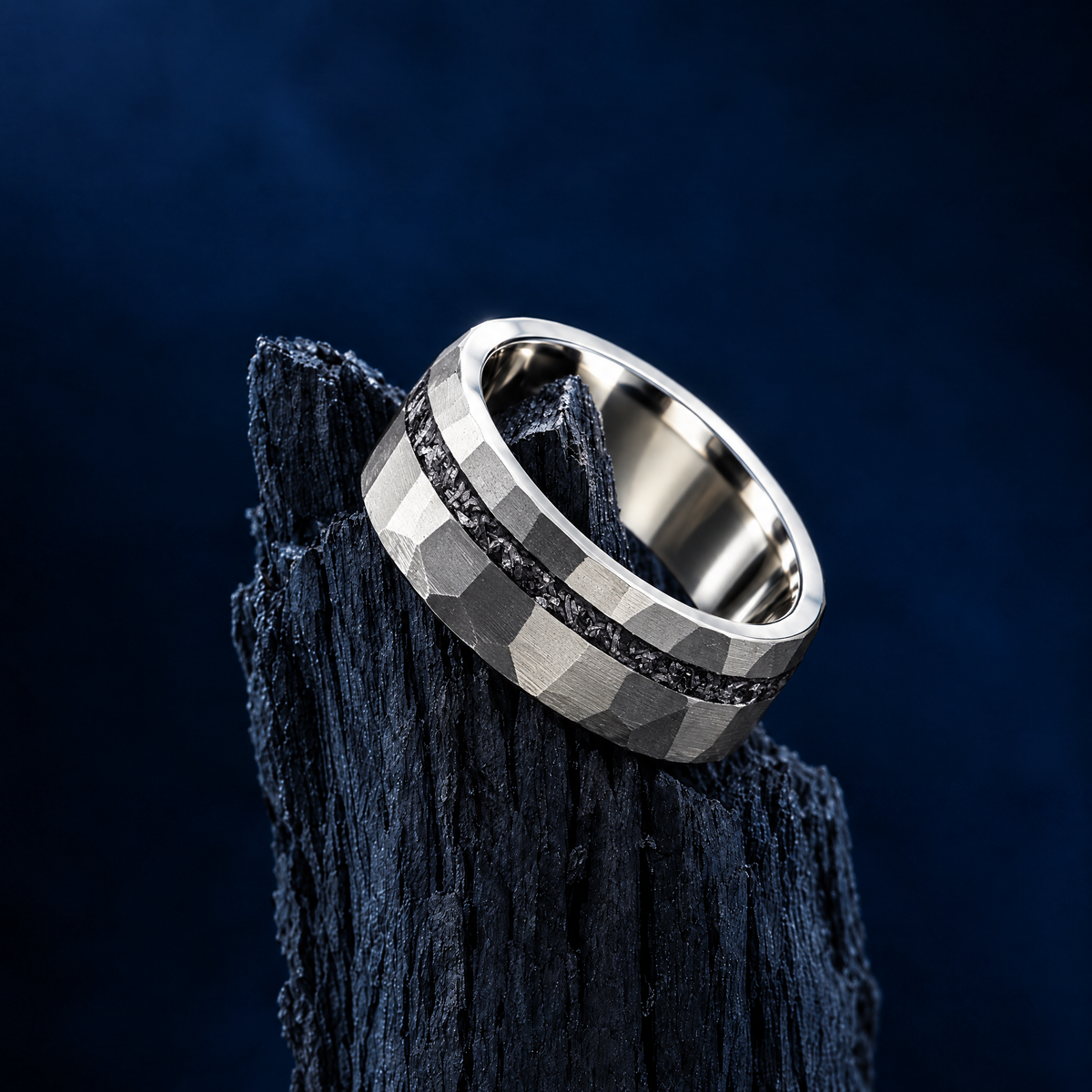 The Nova silver titanium ring with meteorite inlay resting on charred wood