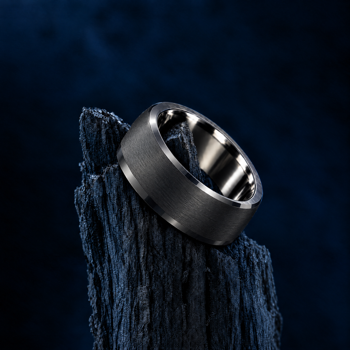 The Keystone black tungsten ring resting on charred wood